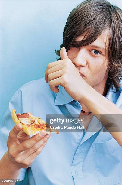 young man eating slice of pizza, high section, close-up - super sensory stock pictures, royalty-free photos & images