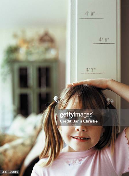 young girl (6-8) measuring height on wall, high section - embrasure de porte photos et images de collection