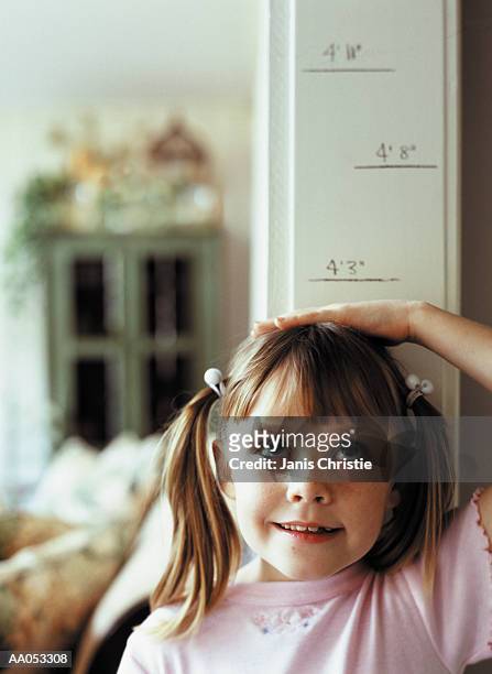 young girl (6-8) measuring height on wall, high section - doorway stockfoto's en -beelden