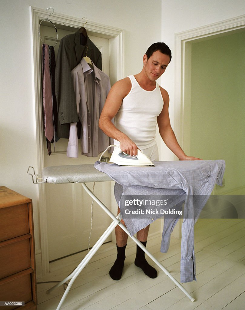 Semi-dressed businessman ironing shirt