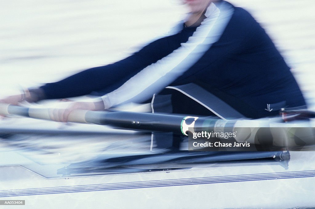 Woman rowing on crew team, mid section (blurred motion)