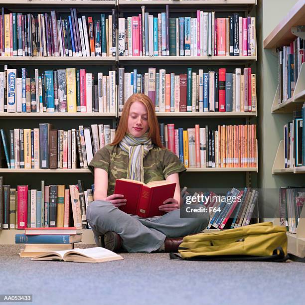 teenage girl (16-18) sitting on floor of library, reading book - f 16 stock pictures, royalty-free photos & images