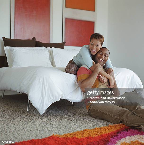 woman sitting on bed, draping arms around man's shoulders, laughing - reed bed stock pictures, royalty-free photos & images