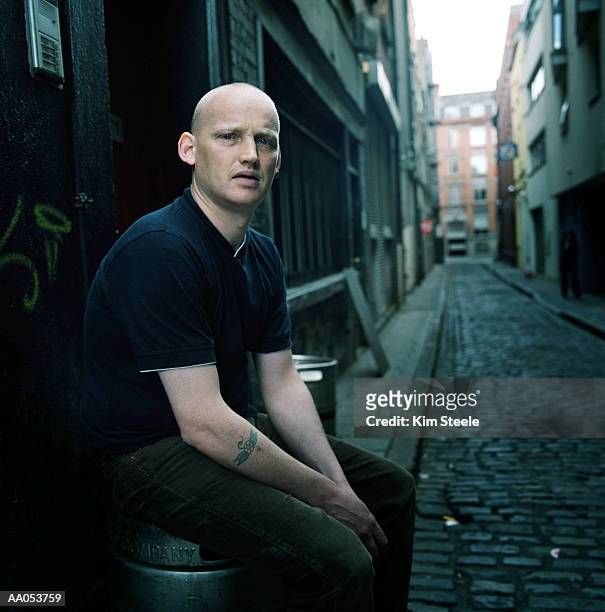 young man sitting on beer keg in alley, dublin, ireland - dublin 個照片及圖片檔