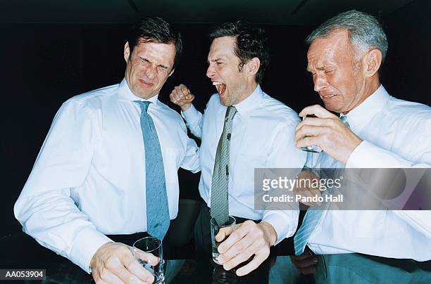 three businessmen drinking shots of liquor, grimacing - liquor stockfoto's en -beelden