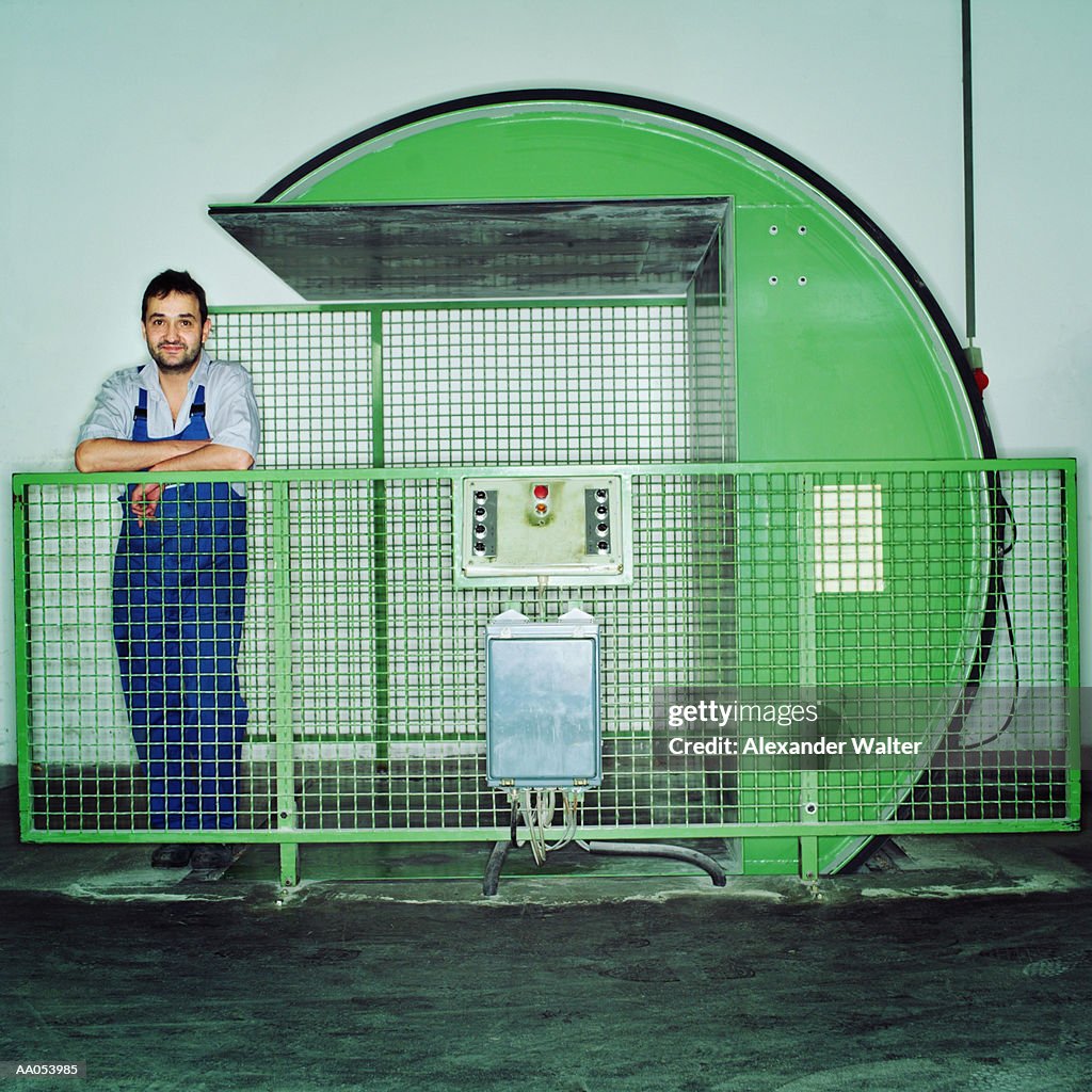 Man standing next to machine which turns paper, printing house