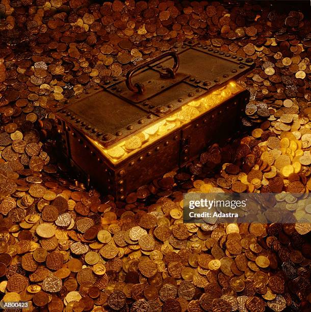 treasure chest surrounded by and full of coins - treasure stock-fotos und bilder