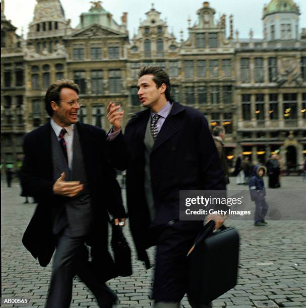 two businessmen walking outdoors, la grande place, brussels, belgium - adult man brussels stock pictures, royalty-free photos & images