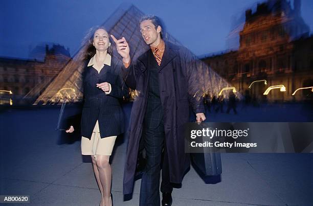 france, paris, couple walking through louvre courtyard, night - louvre pyramid stock pictures, royalty-free photos & images