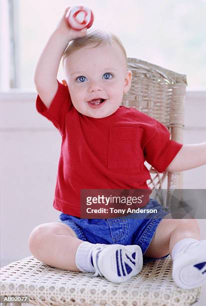 baby boy (9-12 months) sitting on chair, holding ball - ball chair stock pictures, royalty-free photos & images