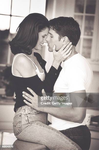 young couple embracing in kitchen (b&w) - nuzzling stockfoto's en -beelden