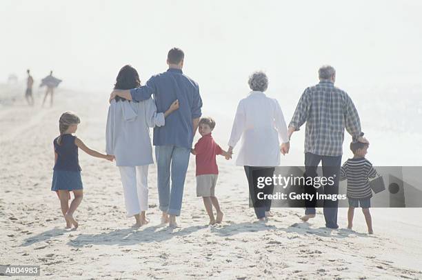 three generation family walking on beach - generation gap stock pictures, royalty-free photos & images