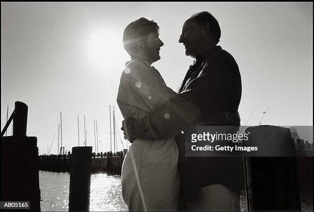 mature couple standing on jetty with moonlight - moonlight lovers fotografías e imágenes de stock