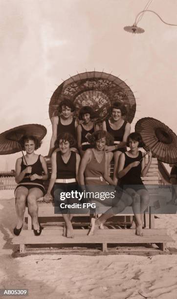 group of women in bathing suits with parasols on bench / 1930's - 1930s beach stock pictures, royalty-free photos & images