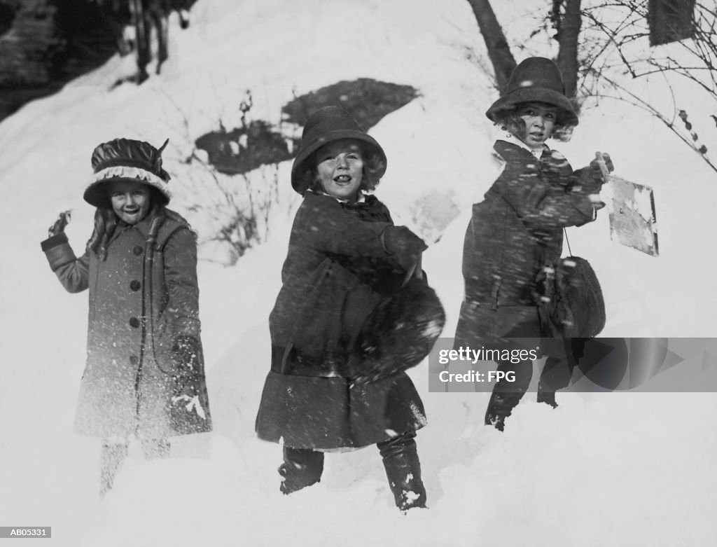 THREE GIRLS IN WINTER COATS, PLAYING IN THE SNOW