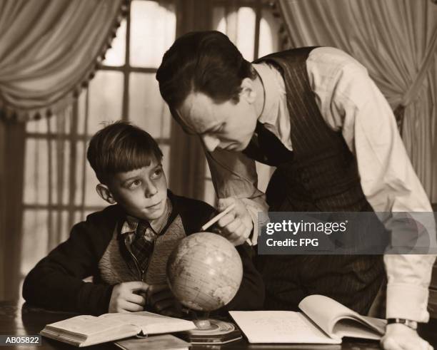 father helping son (10-12) with geography homework (b&w sepia tone) - 1950s father stock-fotos und bilder