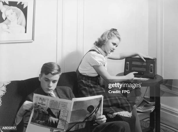 boy and girl (12-15) at home reading and listening to radio (b&w) - listening to radio stock pictures, royalty-free photos & images