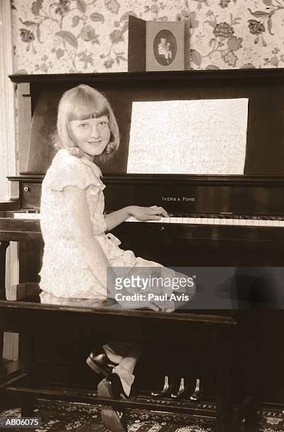 girl (10-12) sitting at piano (toned b&w) - 20th century style stock-fotos und bilder