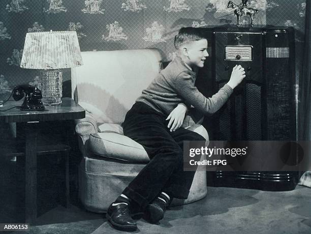 teenage boy (13-15) tuning radio (b&w) - radio stockfoto's en -beelden