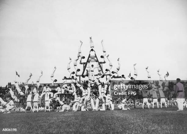 group of male gymnasts forming pyramid on athletic field (b&w) - human pyramid stock pictures, royalty-free photos & images