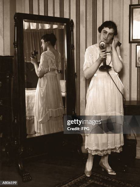 woman using telephone, standing by mirror (b&w sepia tone) - woman full length mirror stock pictures, royalty-free photos & images