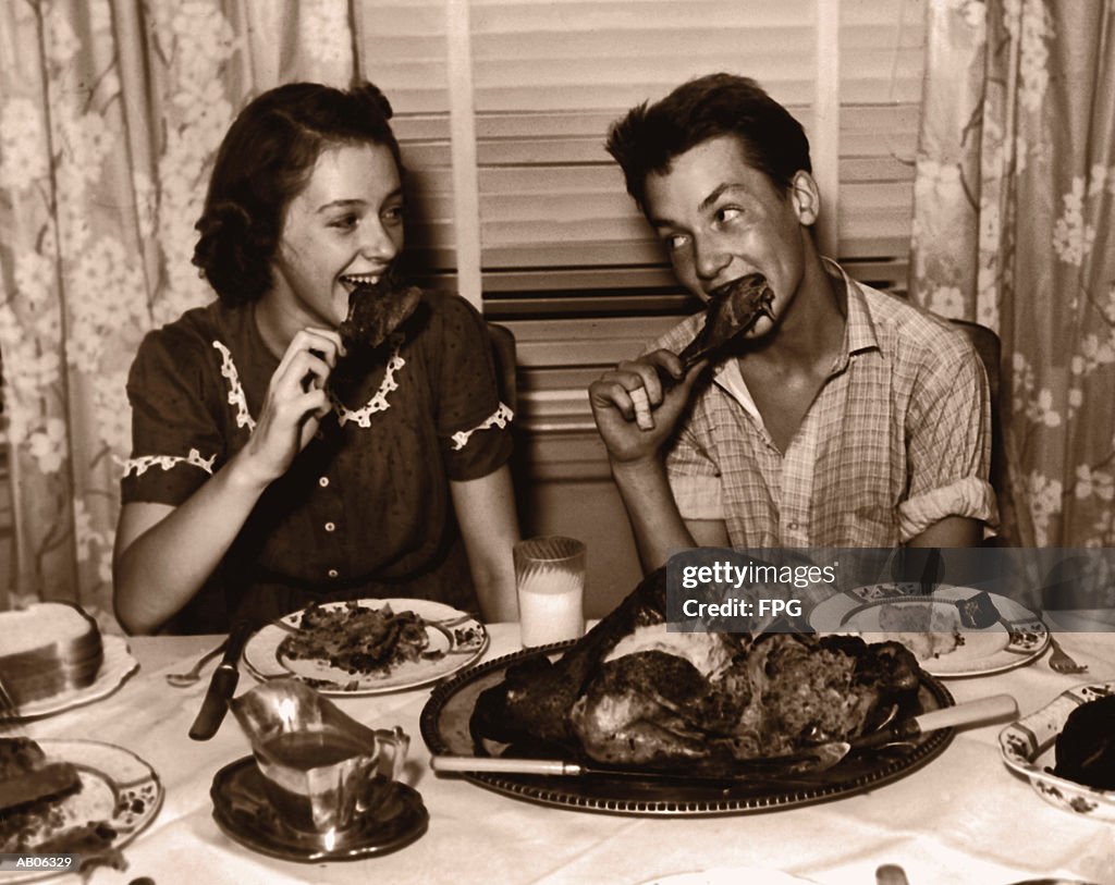 Teenage girl and boy (15-17) eating turkey dinner (B&W sepia tone)