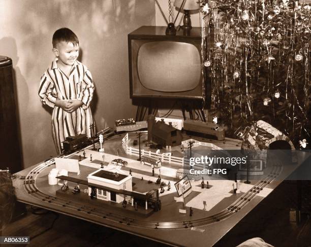 boy (6-8) looking at model train set on christmas day(b&w sepia tone) - christmas train set photos et images de collection