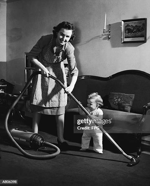 mother and baby boy (12-15 months) holding vacuum cleaner (b&w) - archive 2005 stock-fotos und bilder