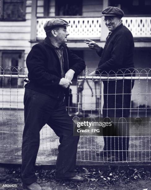 two mature men talking over fence (b&w) - schwätzchen mit dem nachbarn stock-fotos und bilder