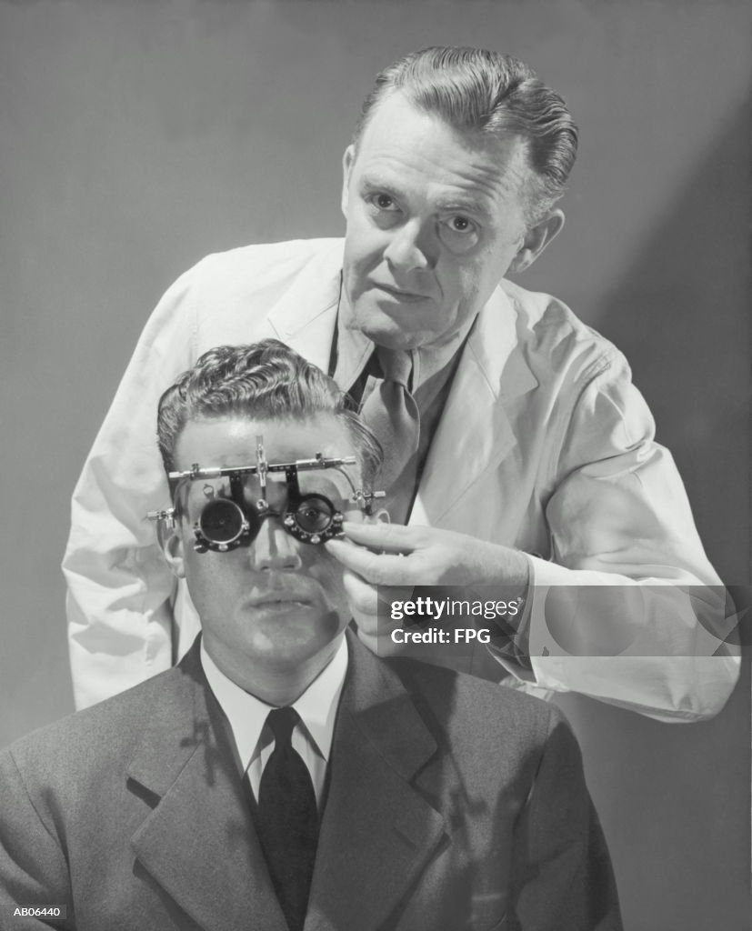 Optometrist giving man eye examination (B&W)