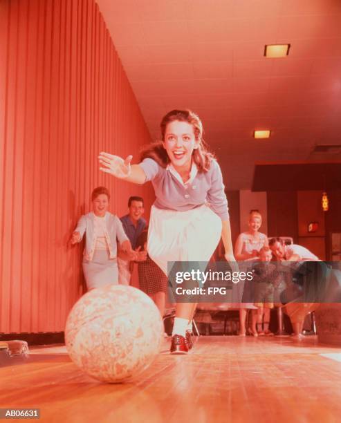 young woman bowling, family watching in background - bowling woman stock-fotos und bilder