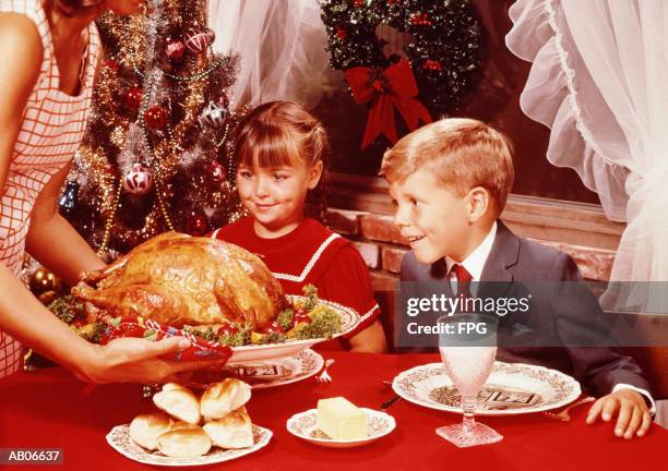mother showing roast turkey to children (7-10) at christmas meal - archiefbeelden stockfoto's en -beelden