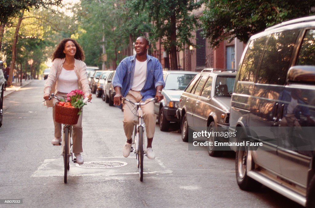 Young couple riding bicycles on urban street