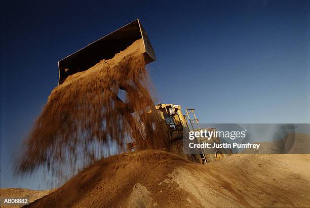 earth mover in quarry dumping sand, low angle view - tractopelle photos et images de collection