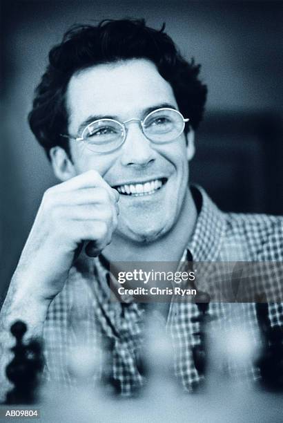 man wearing glasses playing chess, smiling (b&w) - b 47 - fotografias e filmes do acervo