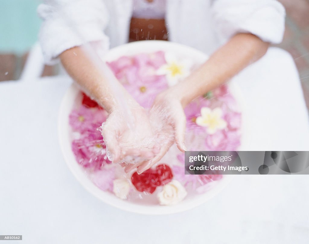 Woman's hands in bowl of floating flowers