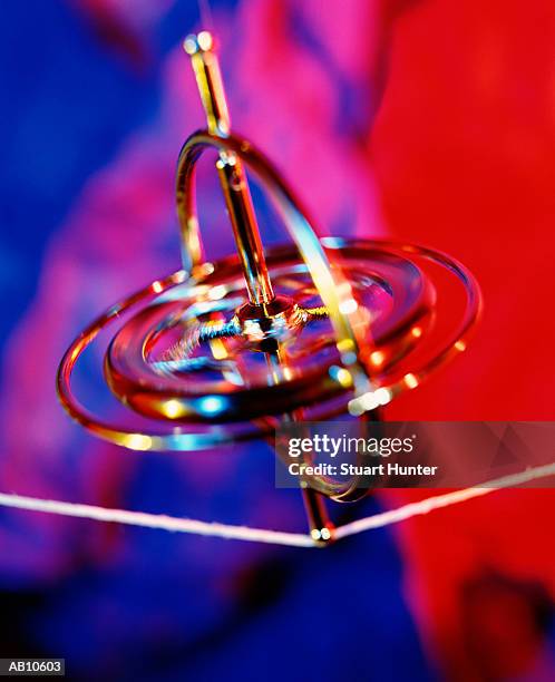 gyroscope balancing on string, close-up (gel effect) - gyroscope stock pictures, royalty-free photos & images
