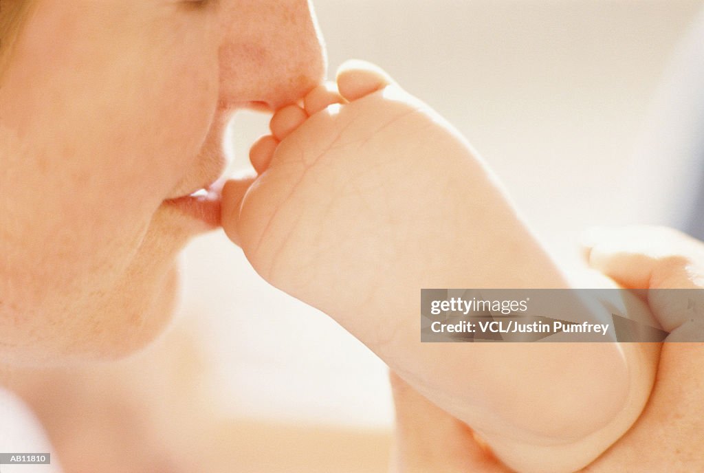 Mother kissing baby's (3-6 months) toes, close up