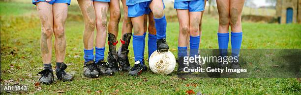 boys standing in row with soccer ball, muddy legs - youth sports competition - fotografias e filmes do acervo
