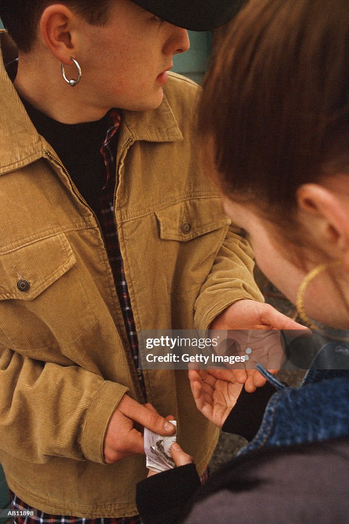 Teenagers (16-18) making drug deal, girl paying boy for pills