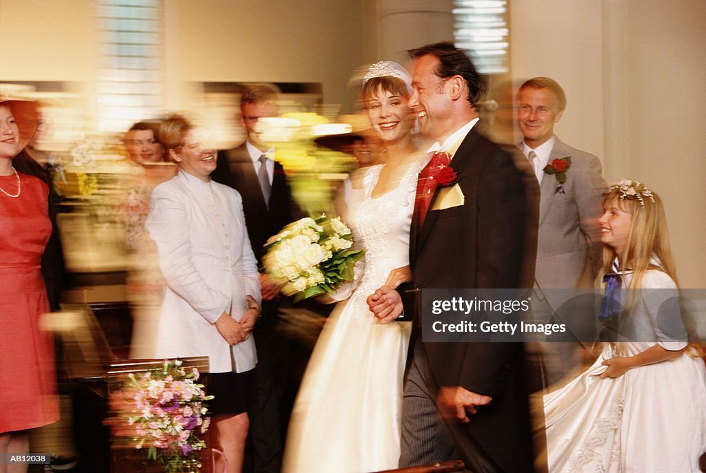 Bride and groom leaving church alter as newlyweds, guests smiling