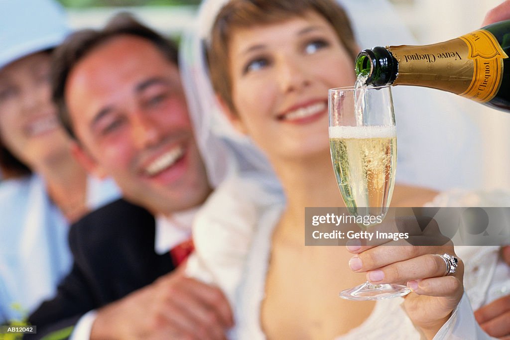 Bride holding glass being filled with champagne
