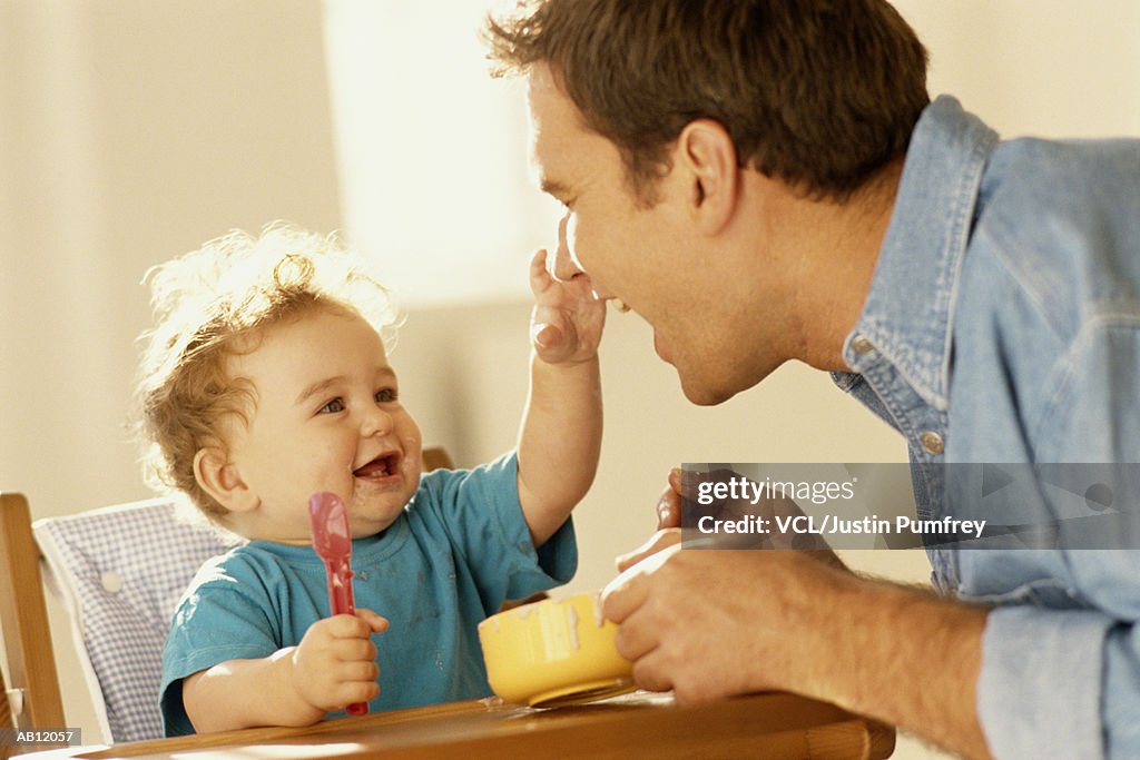 Father feeding baby (6-9 months), close up