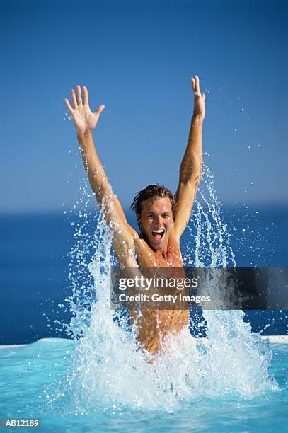 man jumping out of water in swimming pool - swimming pool jump stock pictures, royalty-free photos & images