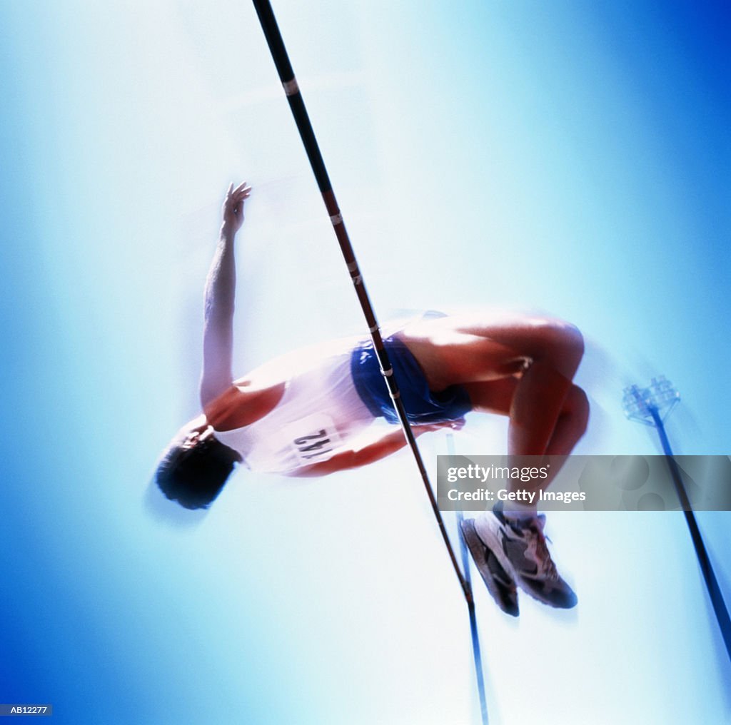 Man clearing high jump bar, low angle, blurred motion