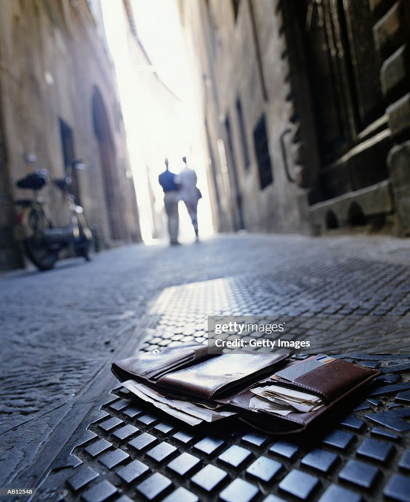 Wallet lying in street with couple walking away in distance