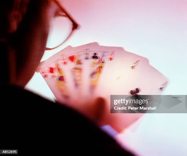 man looking at playing cards, rear view (defocused) - volles haus stock-fotos und bilder
