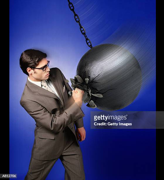 businessman punching into demolition ball as it swings by - wrecking ball stock pictures, royalty-free photos & images
