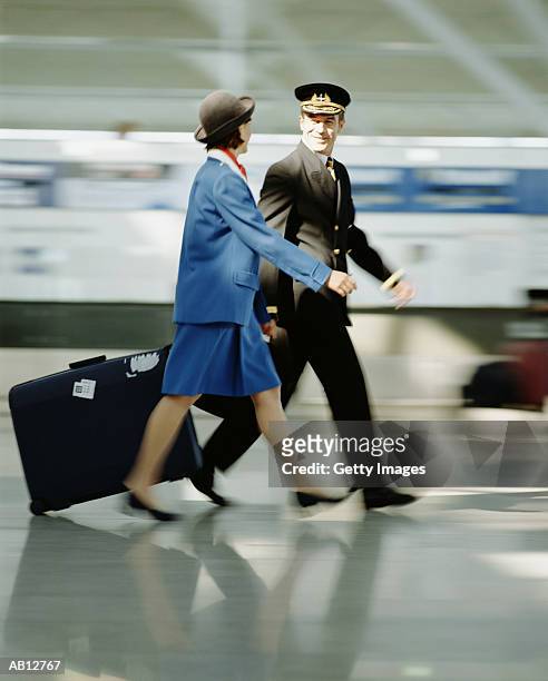 pilot walking with stewardess in airport - stansted airport stock pictures, royalty-free photos & images