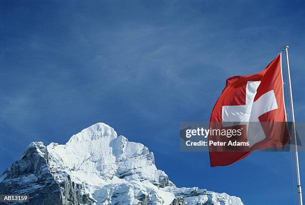 switzerland, wetterham, swiss flag on snow-covered mountain peak - flagge schweiz stock-fotos und bilder